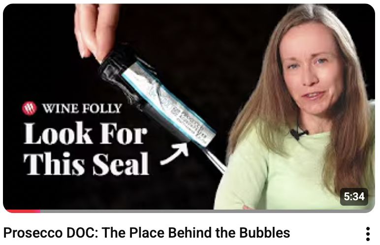 YouTube thumbnail for the opening film in the series, 'Prosecco DOC: The Place Behind the Bubbles.' Wine Folly host on the right, a Prosecco bottle on the left, and the overlay 'Look For This Seal' pointing to the DOC band on the neck.